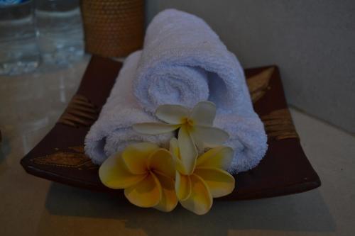 ein Handtuch und zwei Blumen auf dem Tisch in der Unterkunft The Akah Cottage in Nusa Lembongan