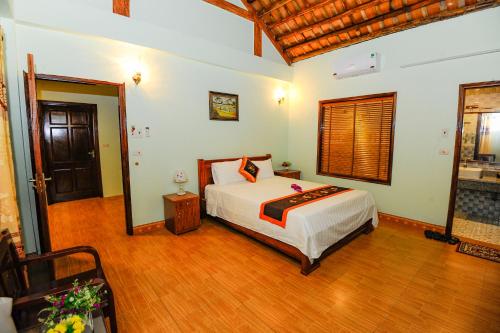 ein Schlafzimmer mit einem Bett und einem Holzboden in der Unterkunft Tam Coc Cosiana Hotel in Ninh Bình