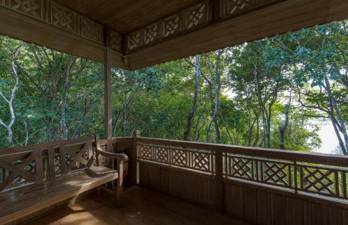 a porch of a house with a bench on it at Menjangan Ecolodge - CHSE Certified in Banyuwedang