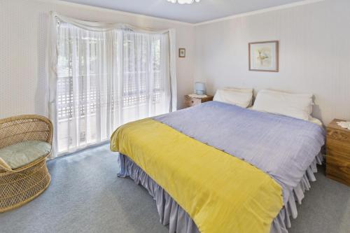 a bedroom with a bed and a large window at Cedar Cottage in Raymond Island