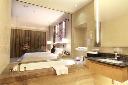 uma casa de banho com uma cama, uma banheira e um lavatório. em Shenzhen Shuidu Holiday Hotel, North Railway Station em Shenzhen