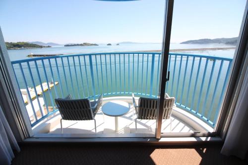 a balcony with two chairs and a table at Hotel Limani in Setouchi