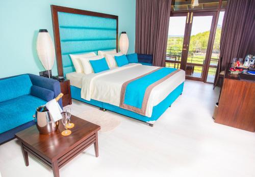 a bedroom with a king sized bed and a blue couch at Amora Lagoon Hotel in Katunayaka