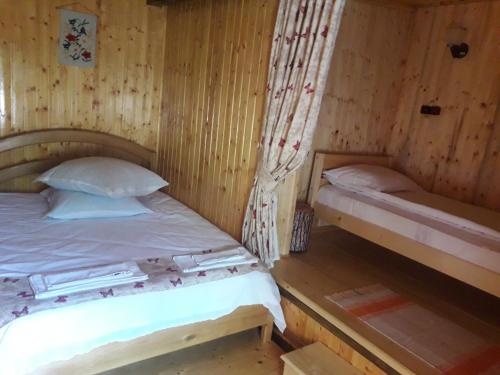 a bedroom with two beds in a wooden room at Casa Bunicii in Costeşti