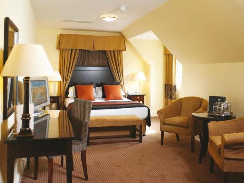 a hotel room with a bed and a desk and a chair at Macdonald Frimley Hall Hotel & Spa in Camberley