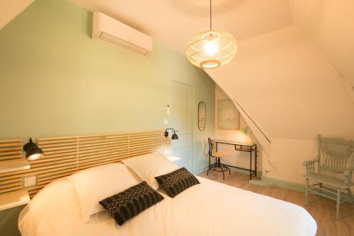 Schlafzimmer mit einem weißen Bett mit einem Kopfteil aus Holz in der Unterkunft Le Nid Douillet, climatisation et parking privé in Sarlat-la-Canéda
