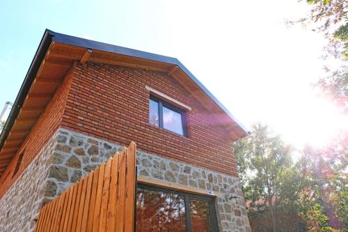 ein Backsteingebäude mit zwei Fenstern und einem Holzzaun in der Unterkunft Lura Agroturizem in Novoberdo
