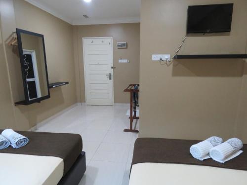 a room with two beds and a tv on the wall at Gm Motel in Kuah