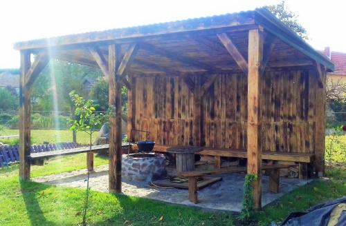 a wooden gazebo with a grill in a yard at Kristály Vendégház in Bogács