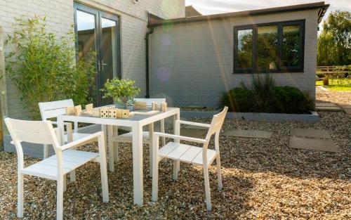 a white table and chairs in front of a house at Bell Lodge in Chichester