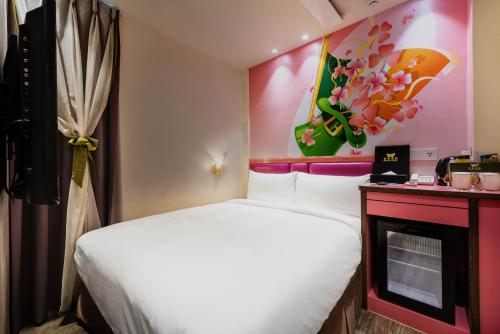 a small bedroom with a white bed and a fireplace at Shichi Hotel in Kaohsiung