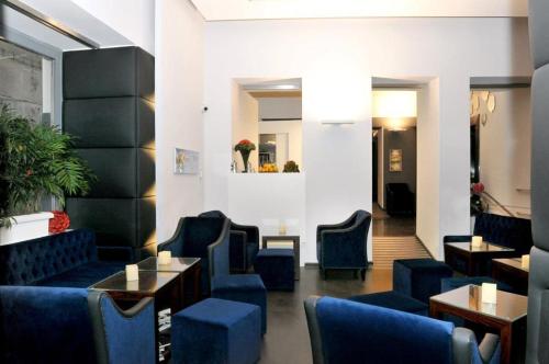 a waiting room with blue chairs and tables at Culture Hotel Centro Storico in Naples