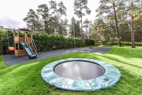 an empty trampoline in the grass with a playground at Vacation Home Mezsargi in Pape