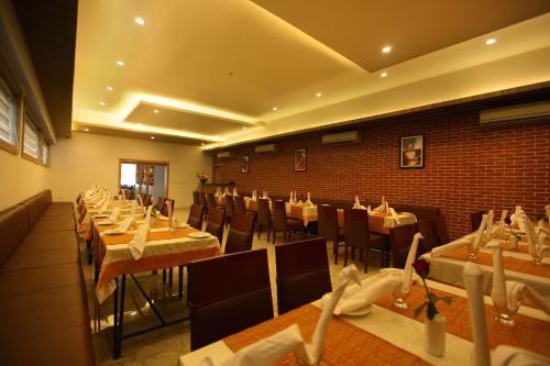 a dining room with tables and chairs and a brick wall at Victory Inn Park Residency in Kunnamkulam