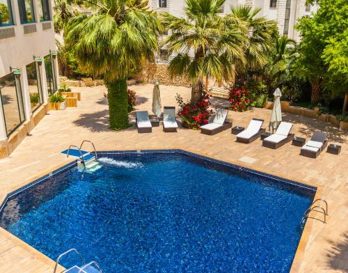 una piscina con sedie a sdraio e un hotel di Amman West Hotel ad Amman