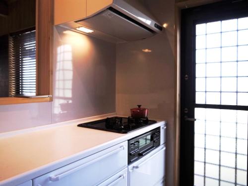 a kitchen with a stove top oven next to a window at Amakusa Ebisu House -天草 えびすHOUSE , 港の前に建つ自然素材の一軒家- in Amakusa