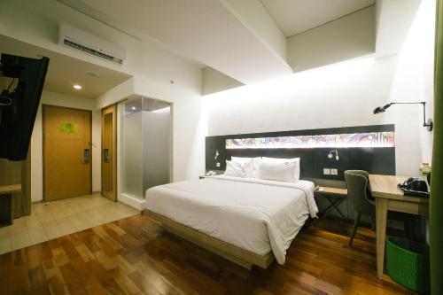 a bedroom with a white bed and a desk and a desk at MaxOneHotels at Dharmahusada Surabaya in Surabaya
