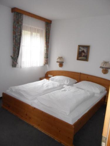 a bedroom with a bed with white sheets and a window at Haus am Römerbad in Bad Kleinkirchheim