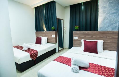 a hotel room with two beds with red pillows at DJ Citi Point Hotel in Kuala Terengganu