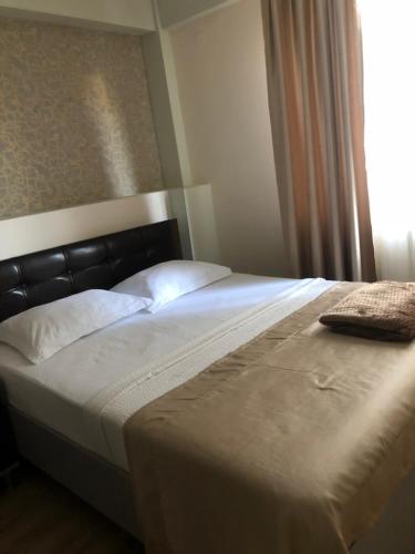 a white bed with a black headboard and white pillows at The K Tbilisi in Tbilisi City