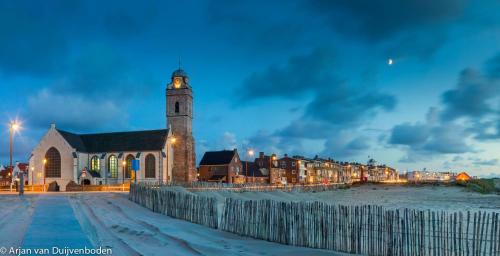 a church with a clock tower at night at Appartement 4 Seasons Katwijk aan Zee in Katwijk aan Zee