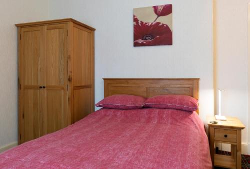 a bedroom with a bed with a pink comforter at Heather Glen Guest House in Elgin
