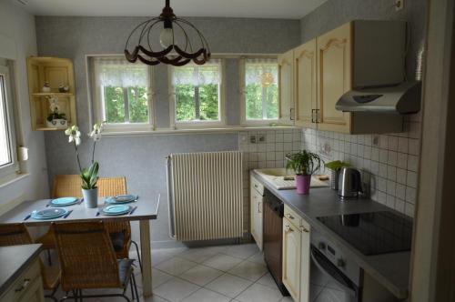 une cuisine avec un évier et une table avec des chaises dans l'établissement Gîte Les Glycines 68230 TURCKHEIM, à Turckheim