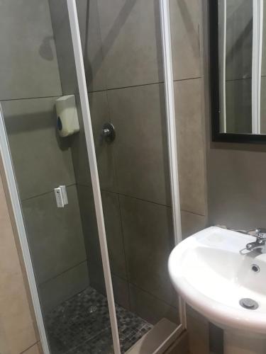 una ducha con una puerta de cristal junto a un lavabo en Amble Inn Guest House, en Empangeni