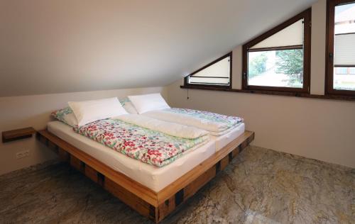 ein großes Bett in einem Zimmer mit zwei Fenstern in der Unterkunft Gästehaus Alte Glaserei in Neustadt an der Weinstraße