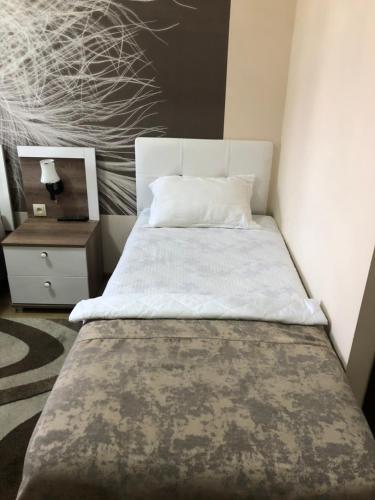 a bedroom with a bed with a white sheets and a night stand at The K Tbilisi in Tbilisi City