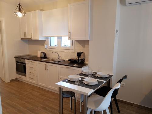 a kitchen with white cabinets and a table and chairs at Fantastic Four Apartments in Neoi Epivates
