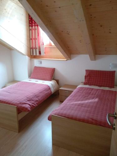 a bedroom with two beds with red sheets at Ciasa Savoy in Vigo di Fassa