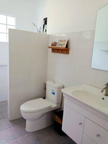 a white bathroom with a toilet and a sink at Sunbeam Cottage in Ko Chang