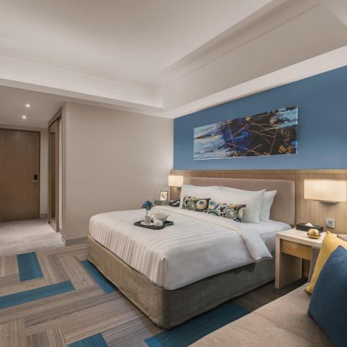 a bedroom with a large bed with a blue wall at Citadines Bay City Manila in Manila