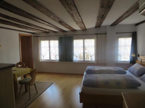 a bedroom with two beds and a desk and windows at Ferienwohnungen Greitmann in Meersburg