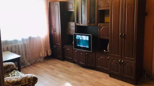 イヴァノヴォにあるЧетырехкомнатная квартира на Любимова 8のリビングルーム(木製キャビネット内のテレビ付)