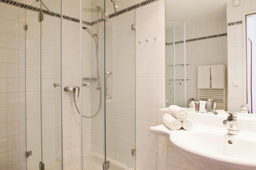 a bathroom with a shower and a sink and a mirror at Hapimag Resort Budapest in Budapest