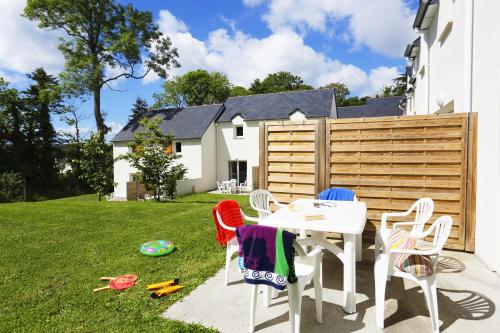 a backyard with a table and chairs and a fence at Terres de France Le Domaine de la Baie in Audierne