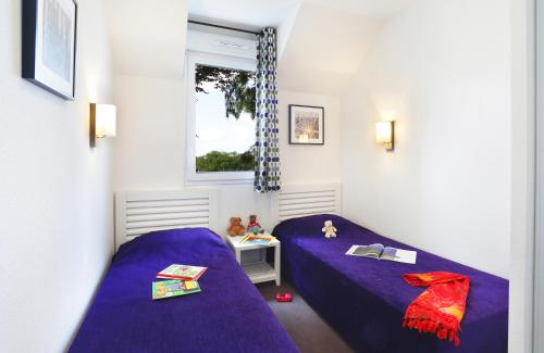 オーディエルヌにあるレジデンス ネメア ル ドメーヌ ド ラ ベの紫のシーツと窓が備わる客室のベッド2台