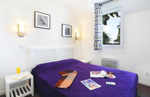 a bedroom with a purple bed and a window at Terres de France Le Domaine de la Baie in Audierne