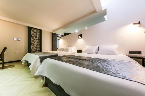 two beds in a hotel room with white walls at Seosan Aria Hotel in Seosan