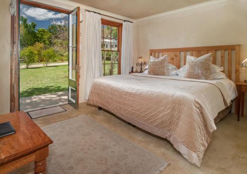 a bedroom with a large bed and a large window at Hotel Roosje van de Kaap in Swellendam