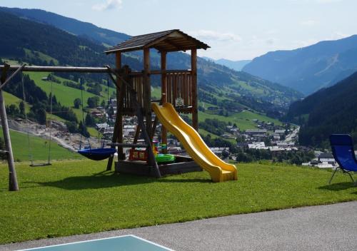 einen Spielplatz mit Rutsche und Stühlen auf einem Hügel in der Unterkunft AlpenHit Saalbach in Saalbach-Hinterglemm