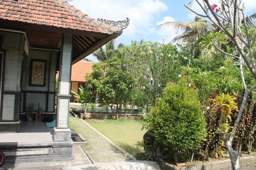 a house with a porch and a yard with trees at Werkudara Guest House in Ubud