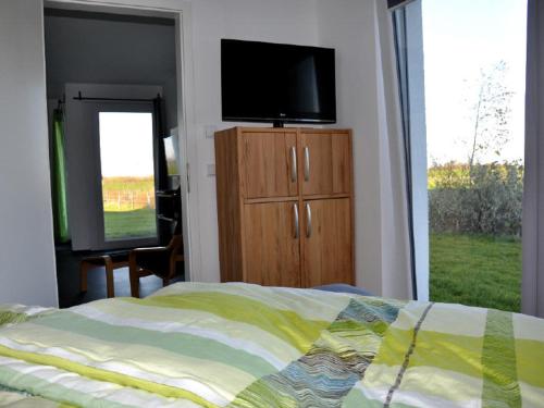 a bedroom with a bed and a television on a dresser at Haus Calmsailing in Börgerende-Rethwisch
