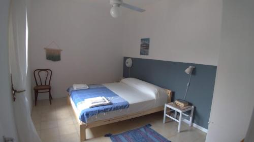 a small bedroom with a bed and a chair at The Greek’ House in Bova Marina