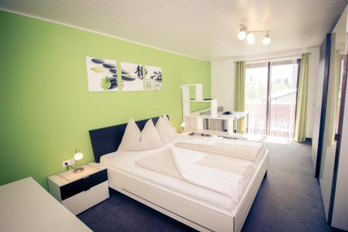 a bedroom with a white bed and a green wall at Pension Waldruh - Tannenheim in Faak am See