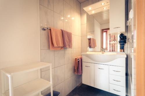 a white bathroom with a sink and a mirror at Pension Waldruh - Tannenheim in Faak am See