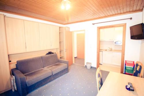 a living room with a couch and a kitchen at Pension Waldruh - Tannenheim in Faak am See