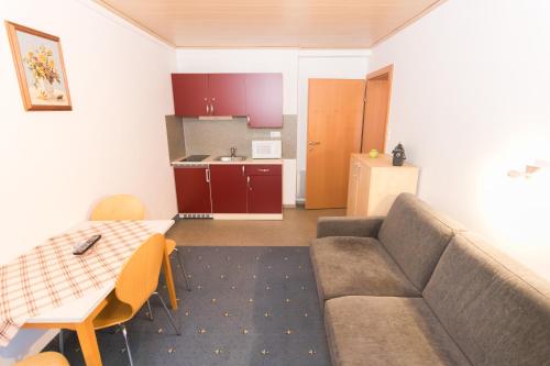 a living room with a couch and a table and a kitchen at Pension Waldruh - Tannenheim in Faak am See